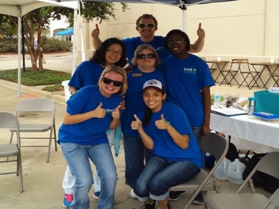 A group wearing blue BVCIL tshirts poses for the camera while smiling and giving a thumbs up. 