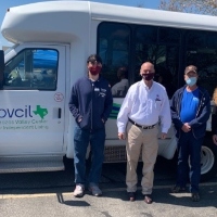 Two BVCIL staff members stand along side Senator John Raney in front of the BVCIL bus. 