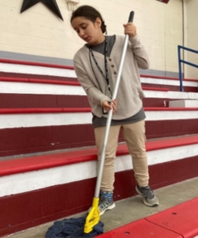 A woman mops red concrete bleachers. 